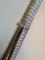 A silver ring with a textured, organic patterned band (coral-like) displayed on a metallic measuring ring stand with size markings.